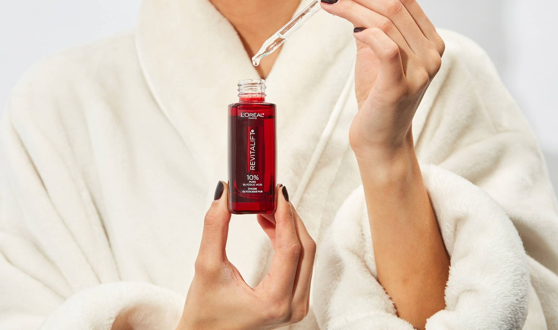 Person wearing a robe using a L’Oréal Revitalift product