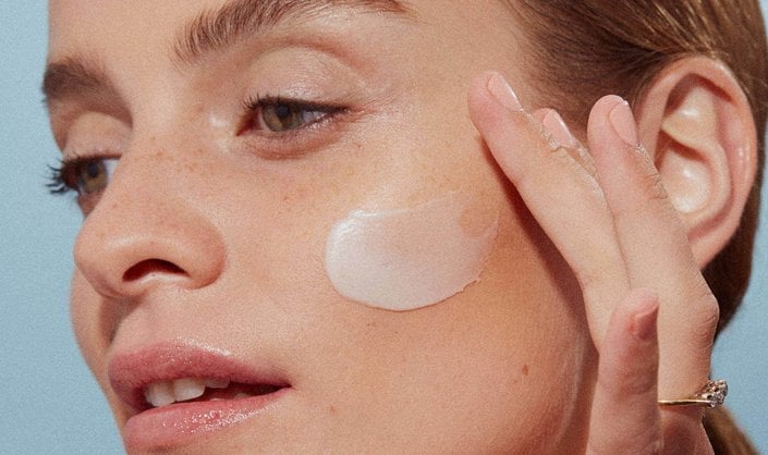 person applying moisturizer to cheekbone