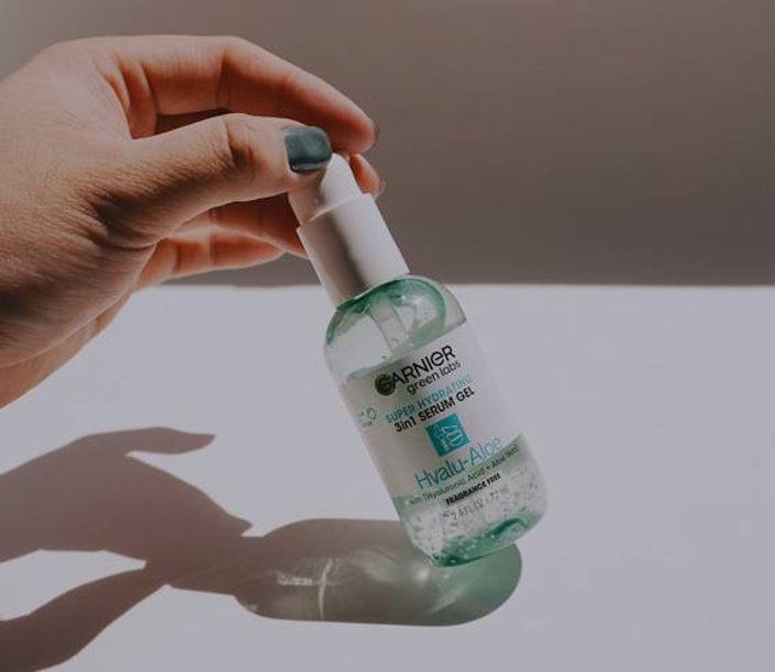 person holding a bottle of garnier green labs hyalu aloe super hydrating serum gel