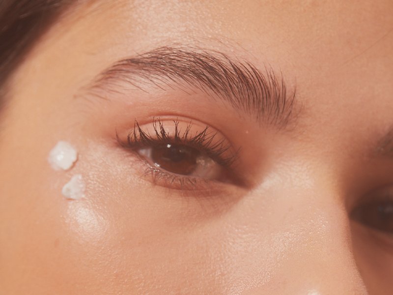 Close-up of person's eye with two dots of eye cream udnerneath