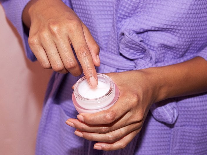 Person dipping finger inside a moisturizer