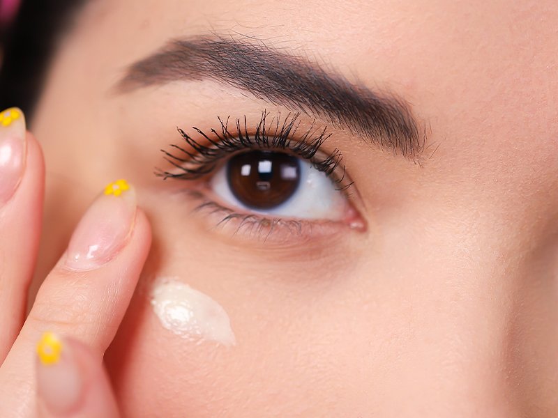 Person putting cream underneath eye