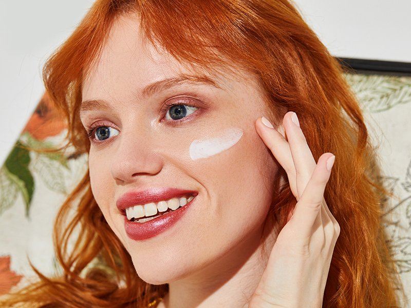 person applying moisturizer to cheekbone