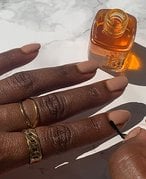 Person painting cuticle oil on nude nails
