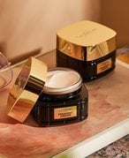 Picture of two of the L’Oréal Paris Age Perfect Cell Renewal Midnight Creams on a wooden tray cast in golden light