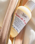 Photo of a bottle of Kiehl’s Creme de Corps sticking out from a pink makeup bag.