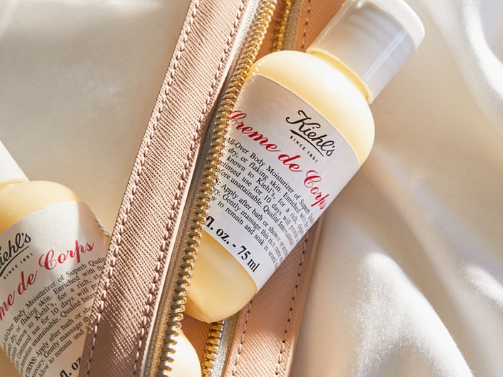 Photo of a bottle of Kiehl’s Creme de Corps sticking out from a pink makeup bag.