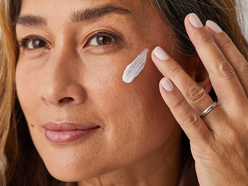 Image of a woman applying moisturizer to her cheek