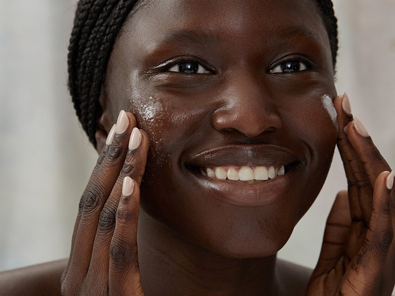 Image of black model washing her face and smiling