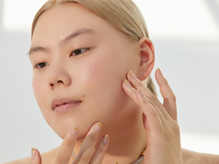 photo of person with gold nails touching their jawline