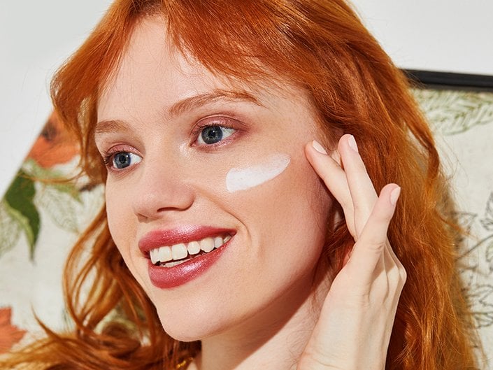 person applying sunscreen to face