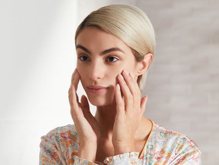 Person looking in a mirror holding hands to cheeks