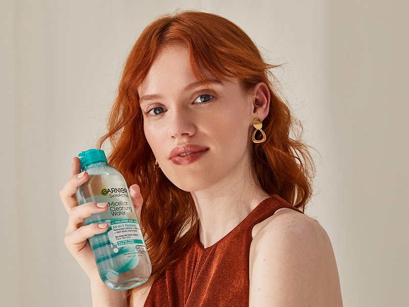 person with red hair holding Garnier SkinActive Micellar Cleansing Water