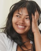 Picture of a model with bangs looking to the side and smiling