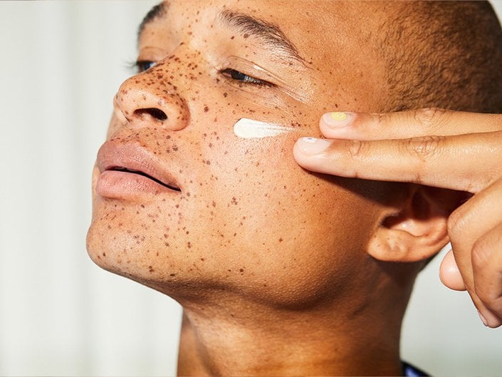 Person applying moisturizer to their cheek