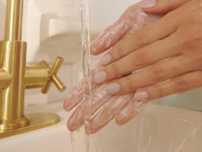 Close-up picture of a person's hands covered in soap under running water