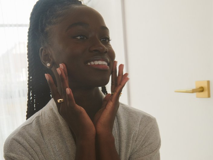 Picture of a model smiling and touching the sides of their face