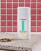 loreal paris bright reveal sunscreen photographed in front of a pink tile background