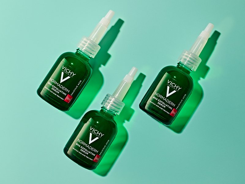 Image of three of the Vichy Normaderm BHA Exfoliating Serums on a green background