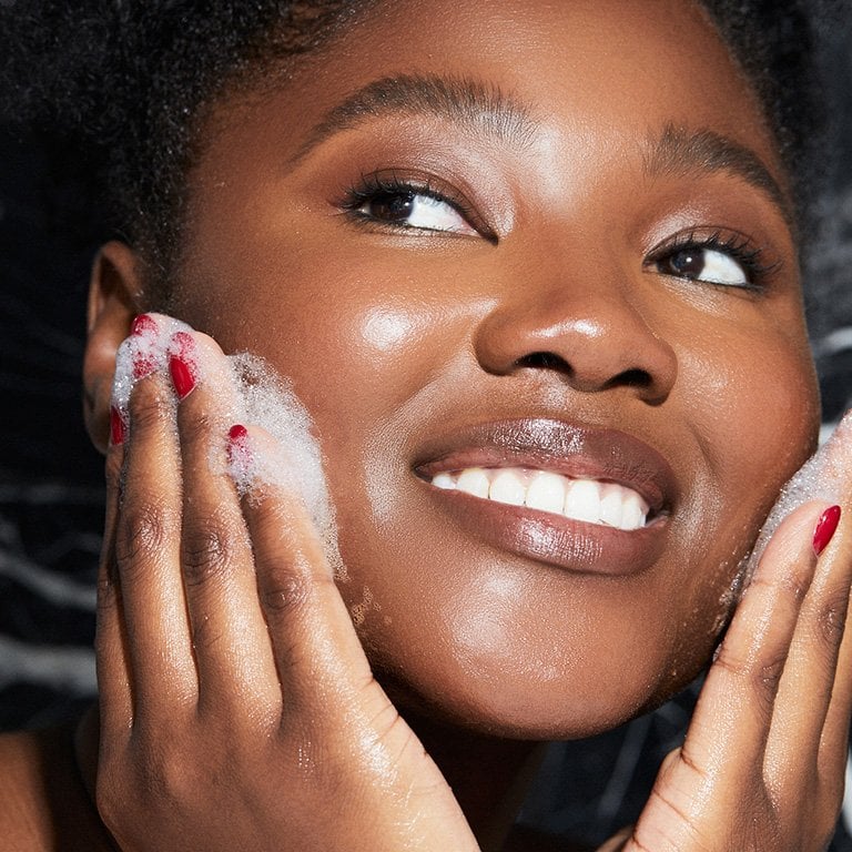 Picture of a person washing their face and smiling