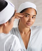 person touching eye area looking in a mirror