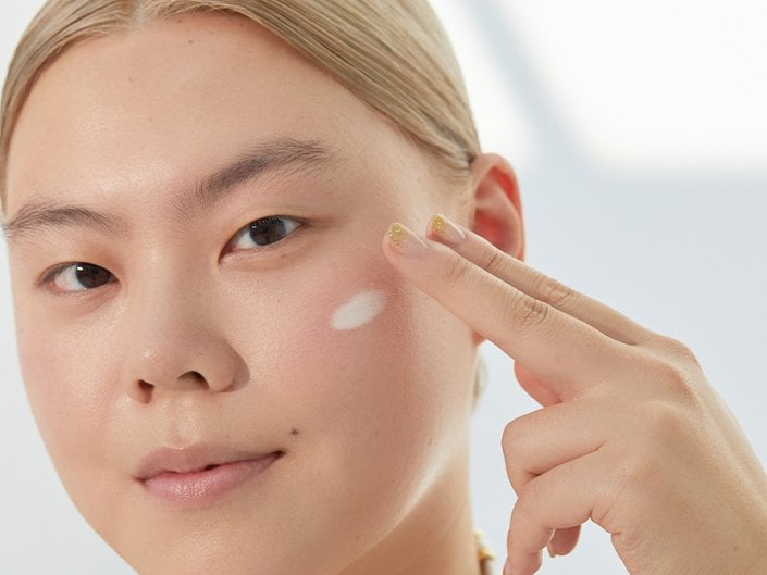 Picture of a model applying cream to their cheek