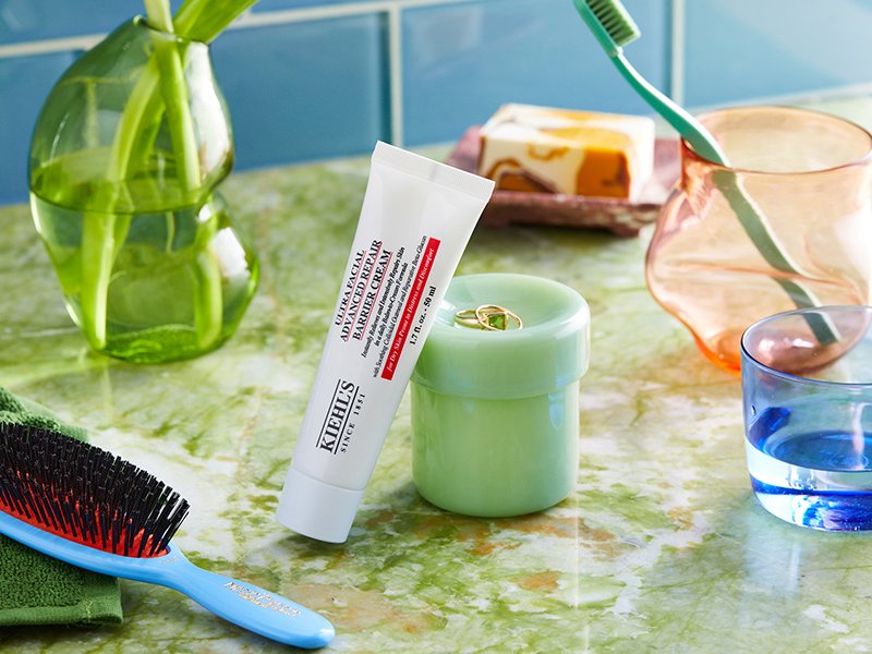 Bathroom countertop with hair brush, toothbrush in a cup, and Kiehl's Ultra Facial Advanced Repair Barrier Cream