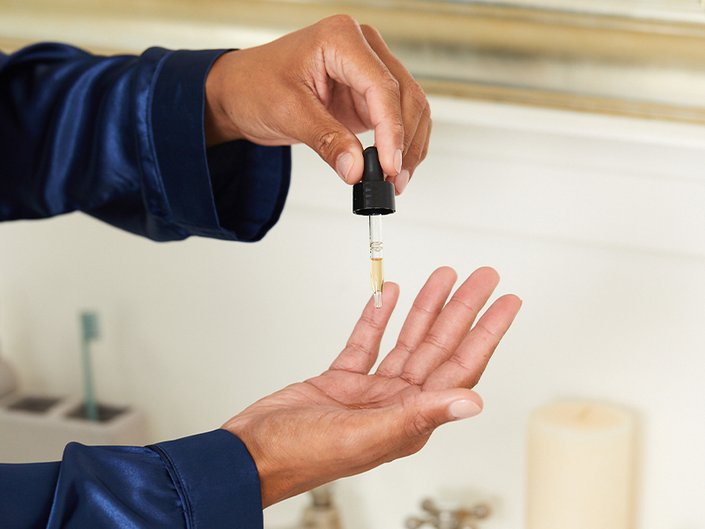 person applying serum to hand with a dropper