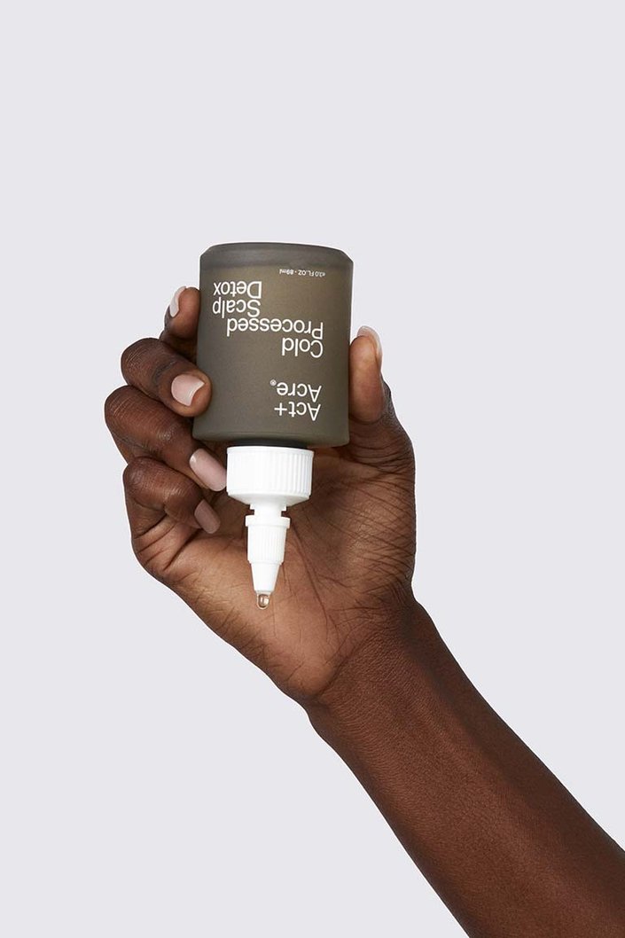 person holding act + acre scalp serum bottle