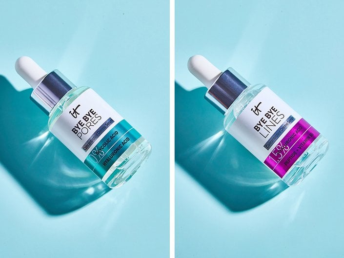 Side-by-side photos of the IT Cosmetics Bye Bye Pores Glycolic Acid Serum and IT Cosmetics Bye Bye Lines Hyaluronic Acid Serum on a light blue background