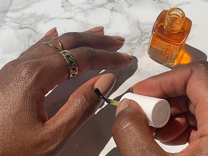 Picture of a person applying cuticle oil to their thumb