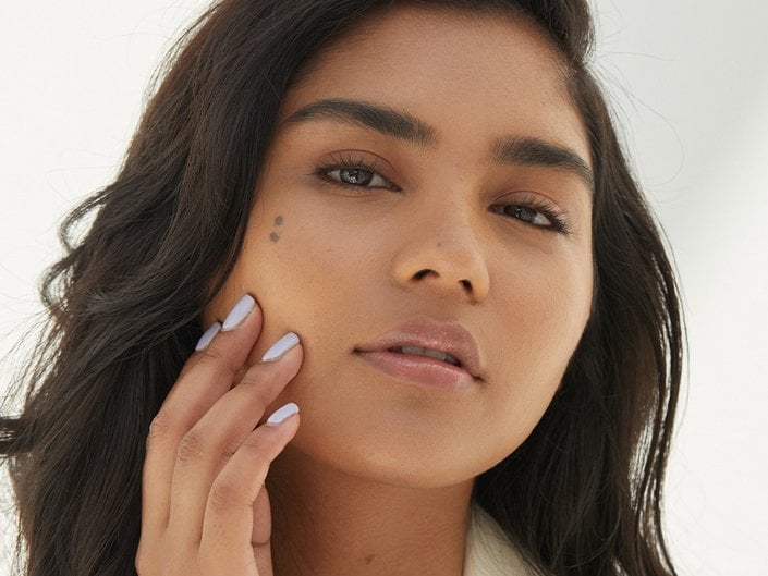 Person with dark hair touching her hand to her face