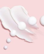 Picture of a white cream swatched on a light pink background