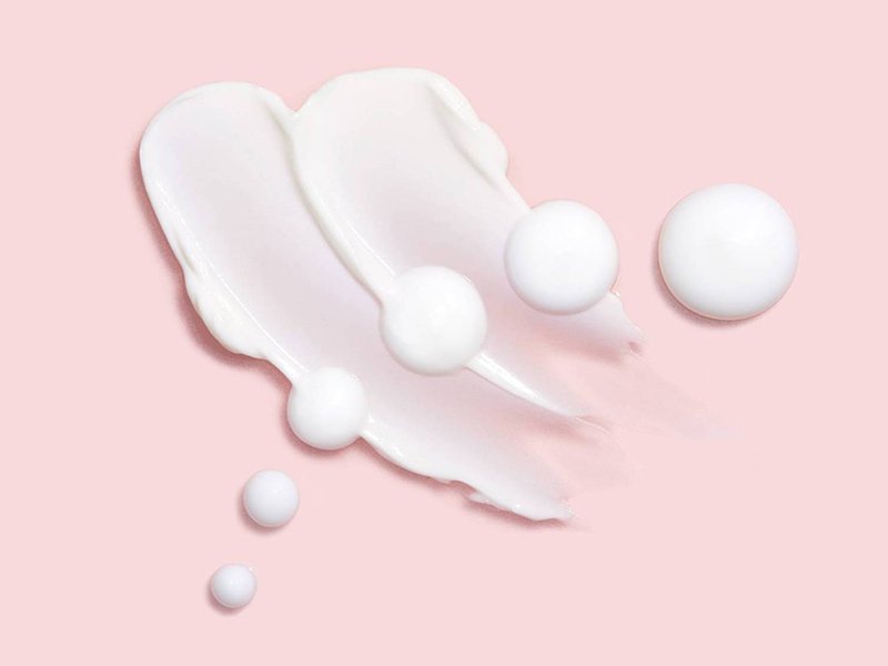 Picture of a white cream swatched on a light pink background