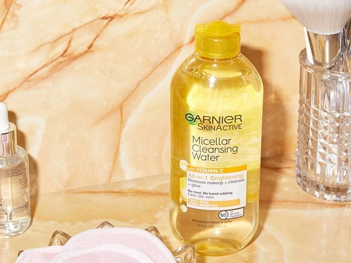A picture of a Garnier mciellar water and skincare tools on a yellow background