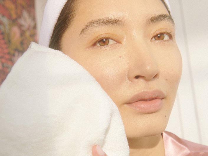 Photo of a model with their hair pulled back washing their face