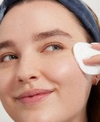 A person wiping their face with a cotton round