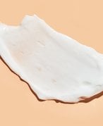 Picture of a swatch of moisturizer on a pale orange background