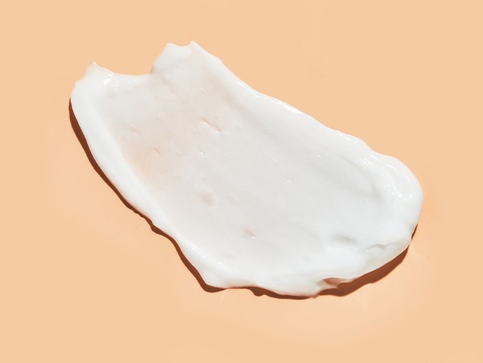 Picture of a swatch of moisturizer on a pale orange background